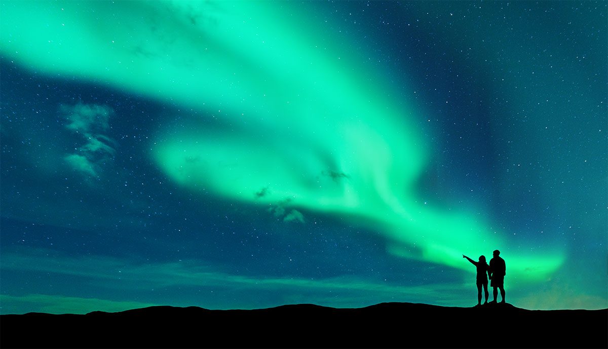 Casal a observar uma aurora boreal na Finlândia.