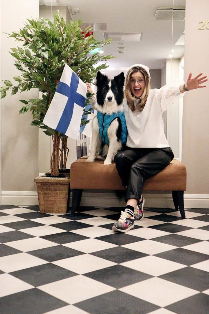 Rafa e Sara sentados num banco do hotel com uma bandeira, em Helsínquia, na Finlândia.