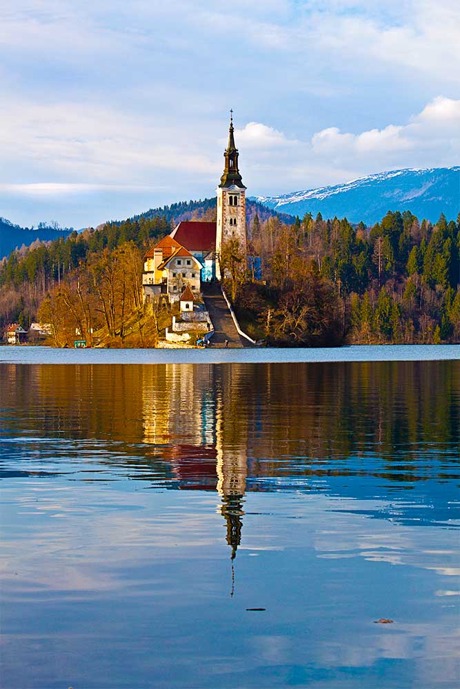 Igreja da Assunção com reflexo no lago, na ilha de Bled, na Eslovénia.