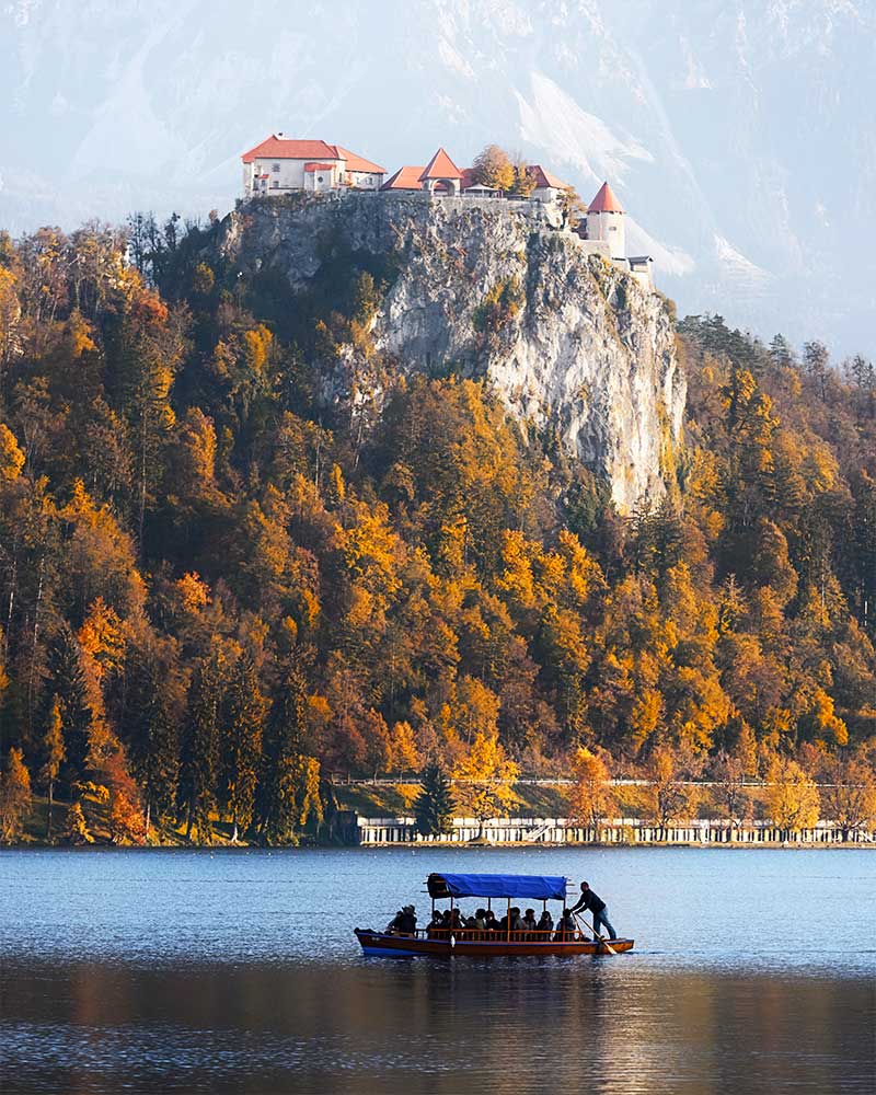 Barco com turistas no Lago Bled e a povoação ao fundo.