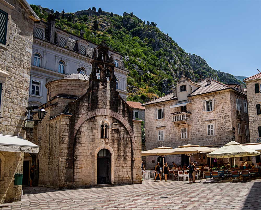 Kotor town square with terraces and a church.
