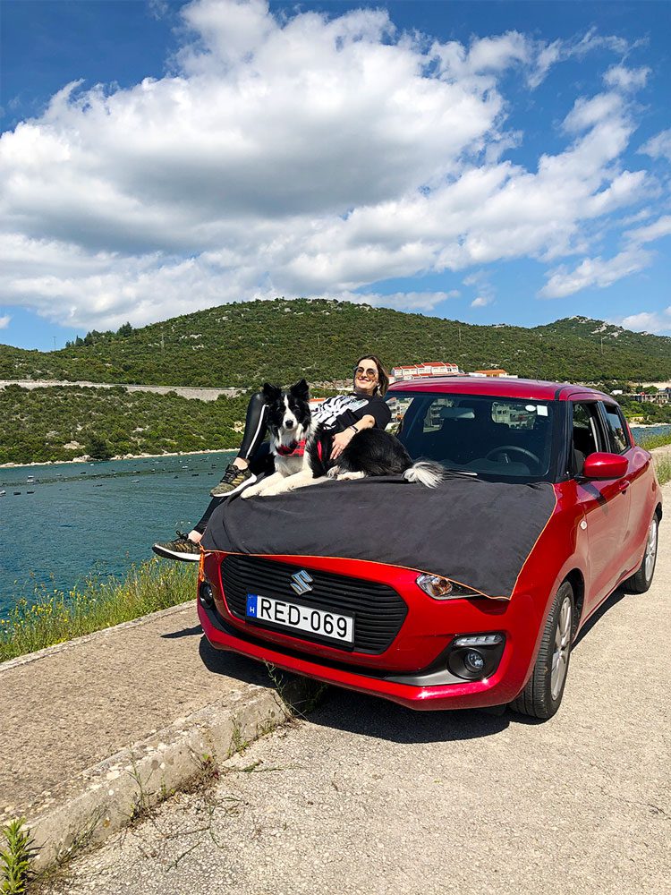 Sara and Rafa lying on the hood of the car sunbathing by the water in Neum