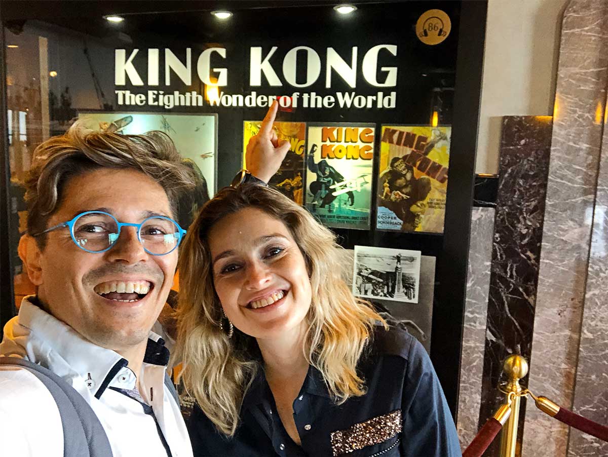 Pedro and Sara next to a poster of King Kong, in the Empire State Building, in New York.