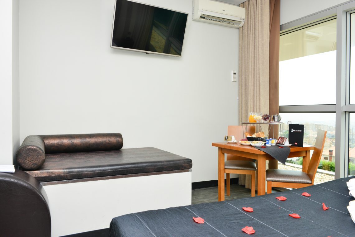 Sofá, televisão e mesa de pequeno-almoço na suite Clássica do Motel Alto de Valongo