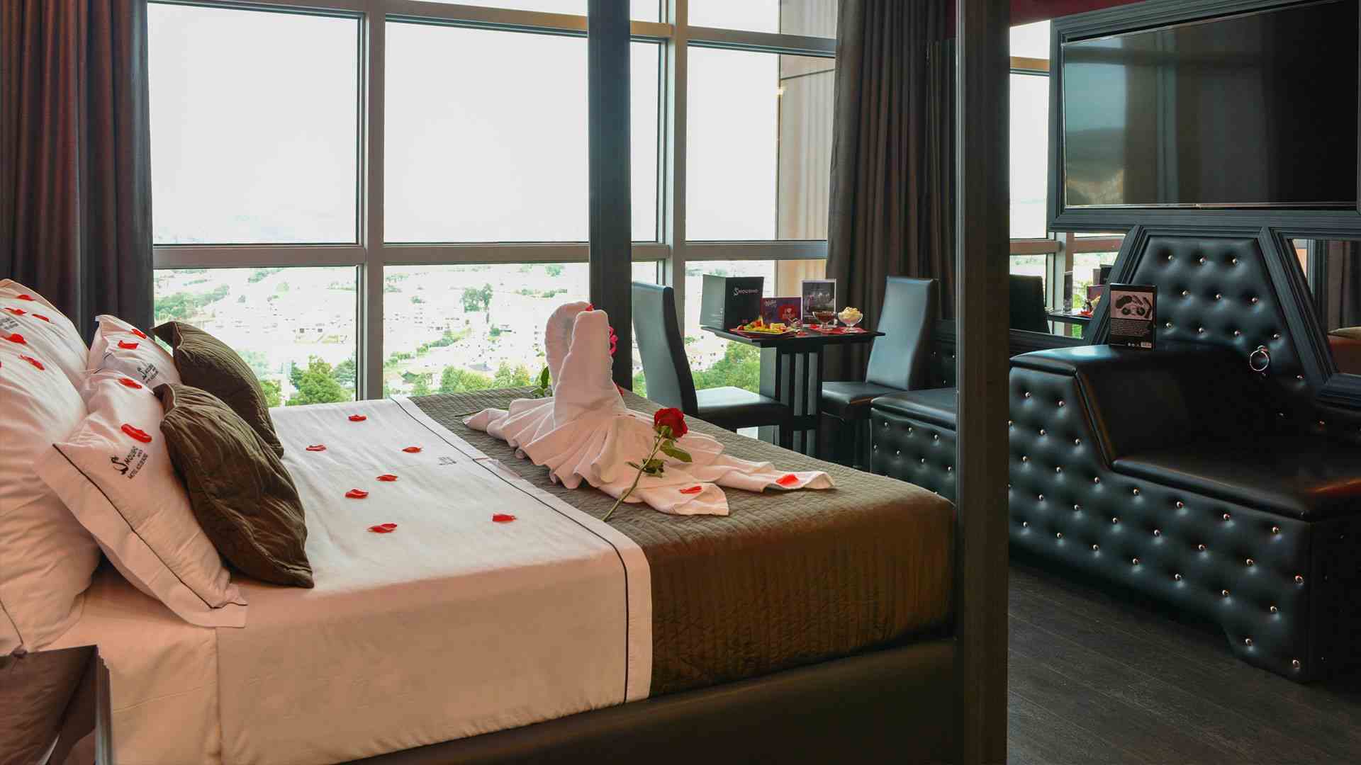 Suite Grey com decoração romântica e sofá preto almofadado, no Motel Alto de Valongo