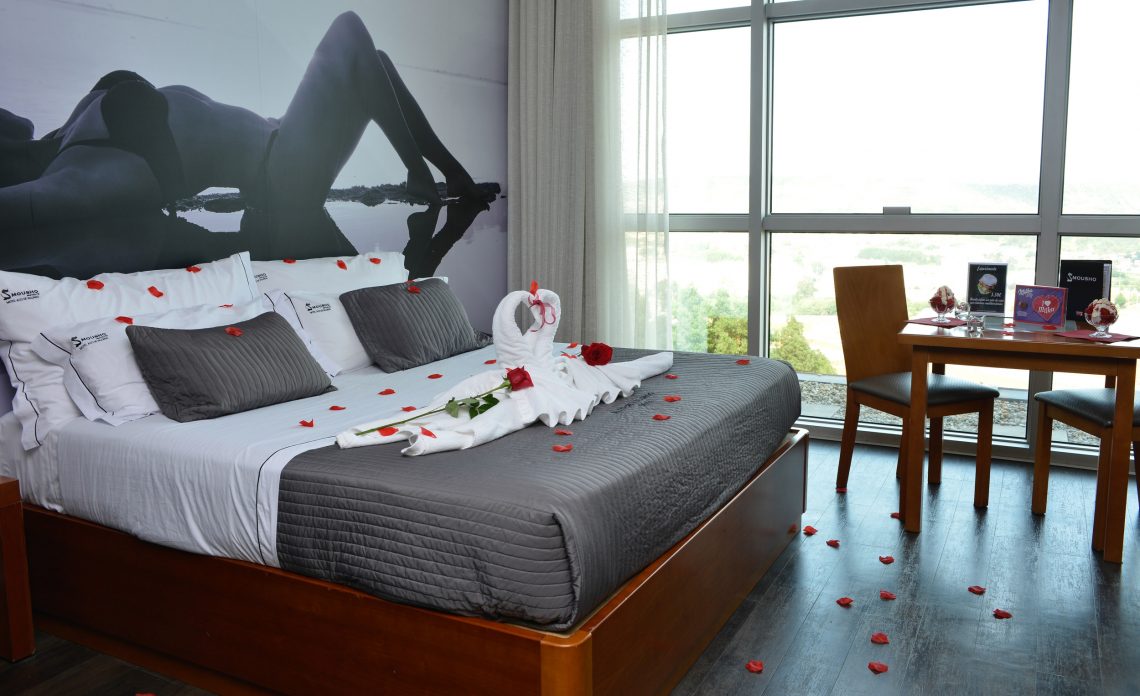Suite Jacuzzi com decoração romântica e duas taças de morangos com chantilly em cima da mesa, no Motel Alto de Valongo