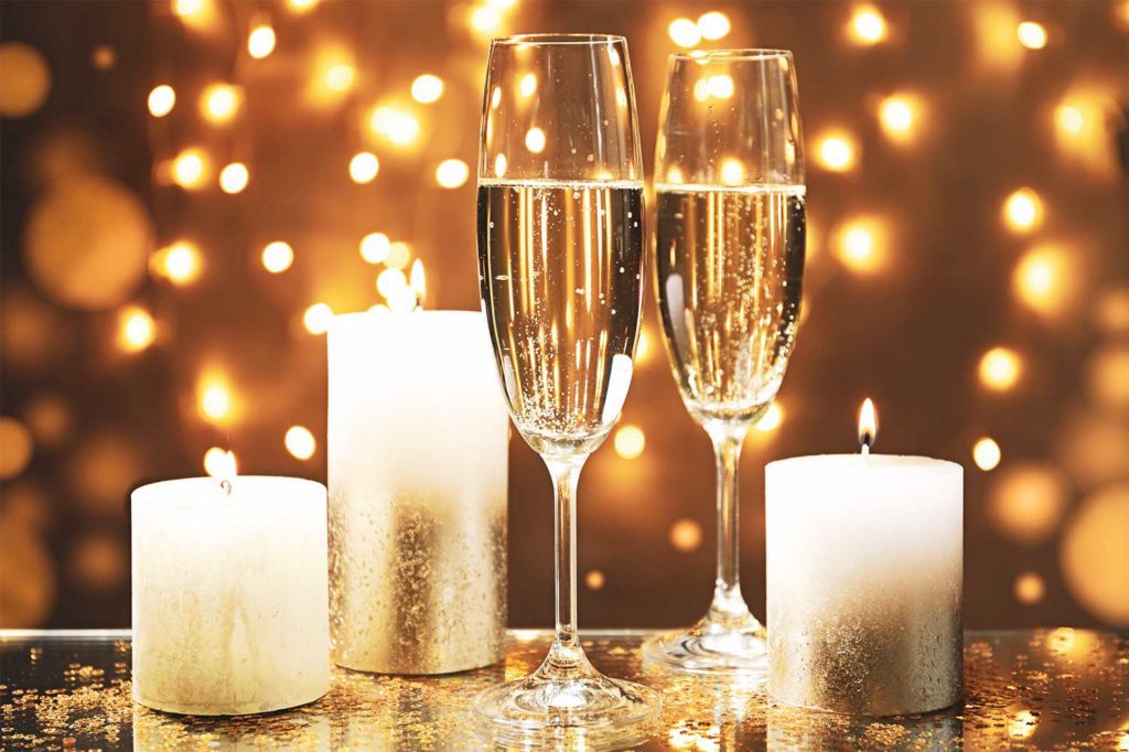 Imagem de velas brancas e duas flutes de champanhe