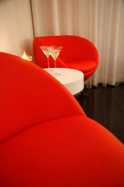 Pormenor de mesa com duas flutes de champanhe e uma vela e em redor da mesa, dois cadeirões vermelhos, na suite Miami.
