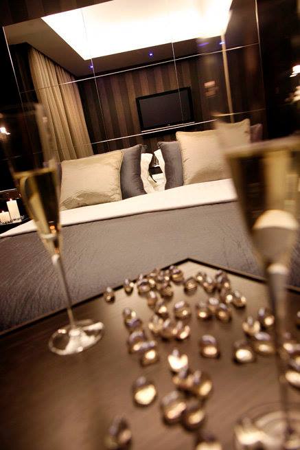 Pormenor de vista da cama ao fundo, com duas flutes de champanhe e berlindes, na suite Nova Iorque, no Motel Flamingo