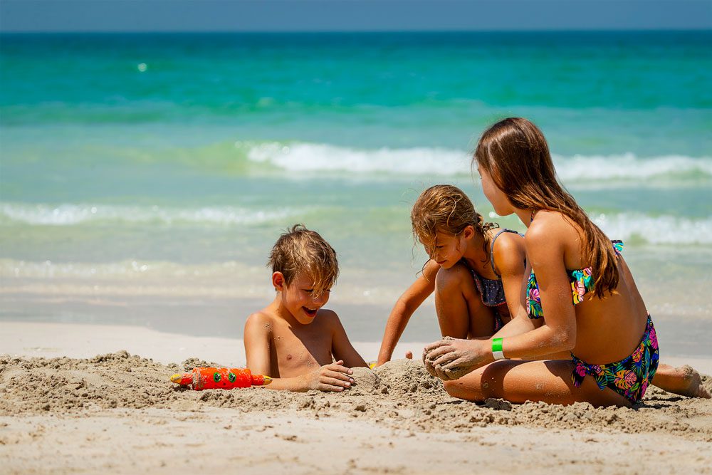 Três crianças a brincar na praia