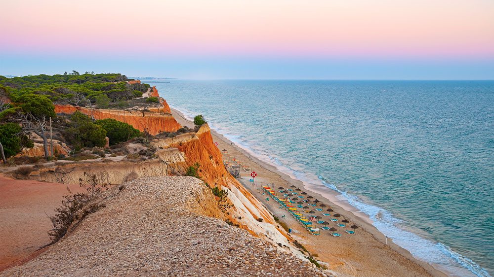 Praia concessionada ao pôr-do-sol, na zona do Algarve, em Portugal