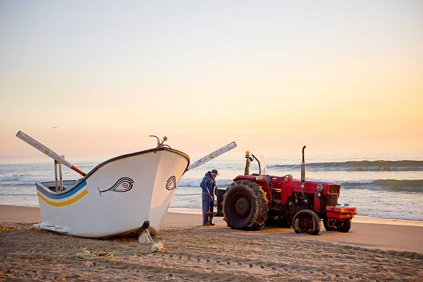 Barco e tractor na praia de Mira ao pôr-do-Sol.