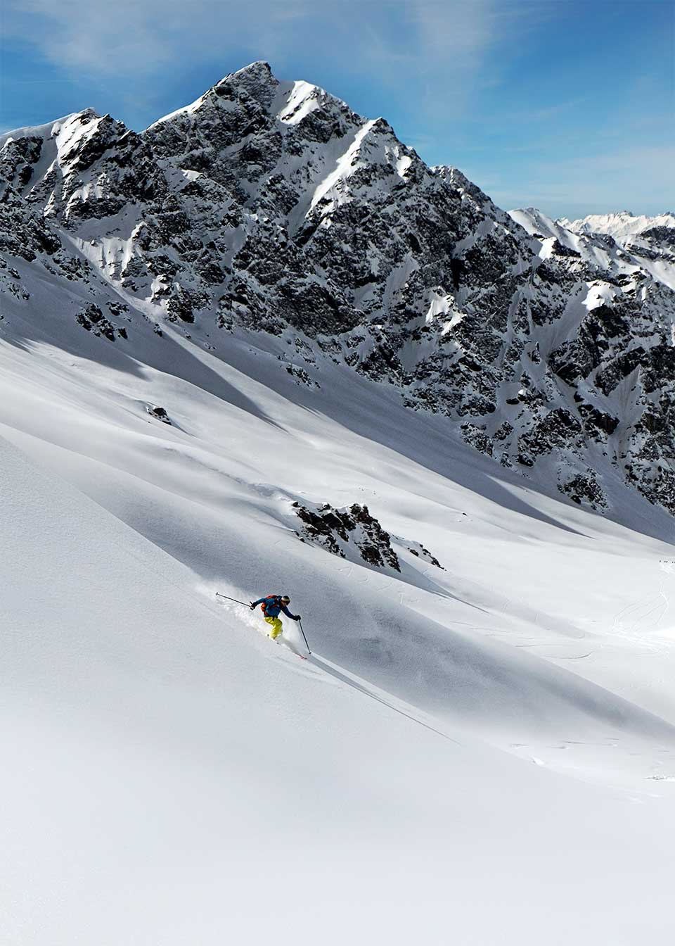 Pessoa a esquiar, descendo uma montanha com neve