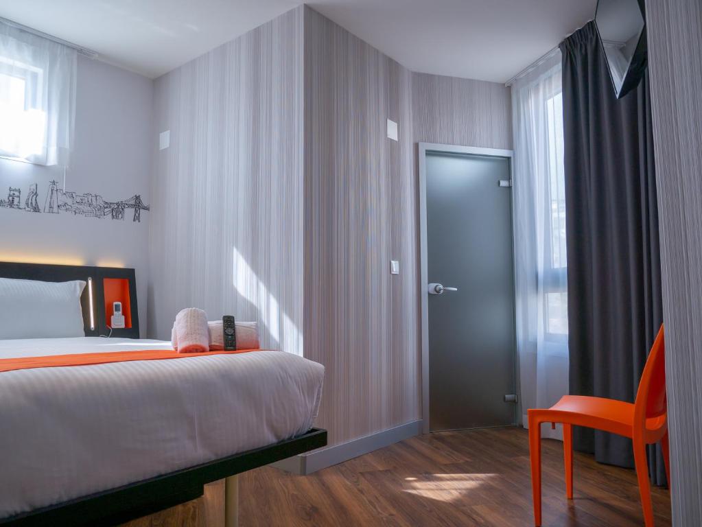 Quarto do Easyhotel Lisbon com decoração em tons de cor de laranja.