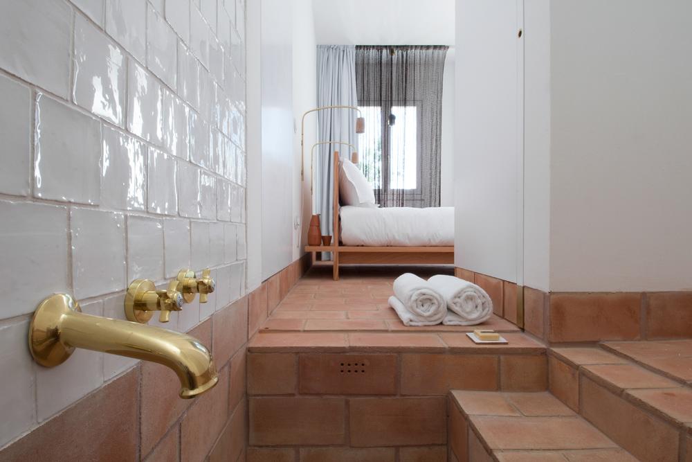Zona de wc com torneiras antigas em quarto com cama de casal, na Casa Modesta, em Olhão