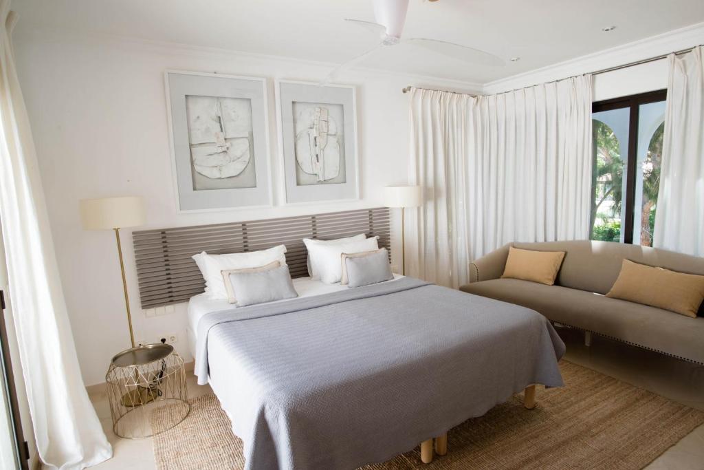 Quarto com cama de casal, sofá e duas janelas, no Pine Cliffs Village Golf & Suites.