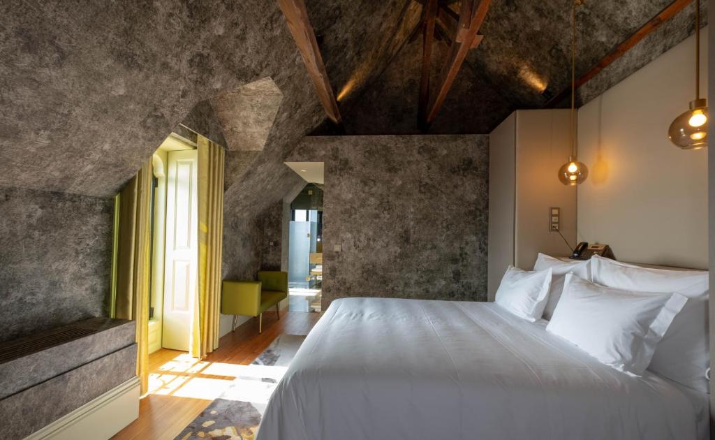 Quarto com cama king size e paredes em pedra, no Vila Foz Hotel & Spa, no Porto